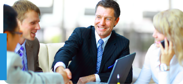Insurance Agency Team Smiling business professionals in suits shaking hands and discussing insurance agency acquisition opportunities.