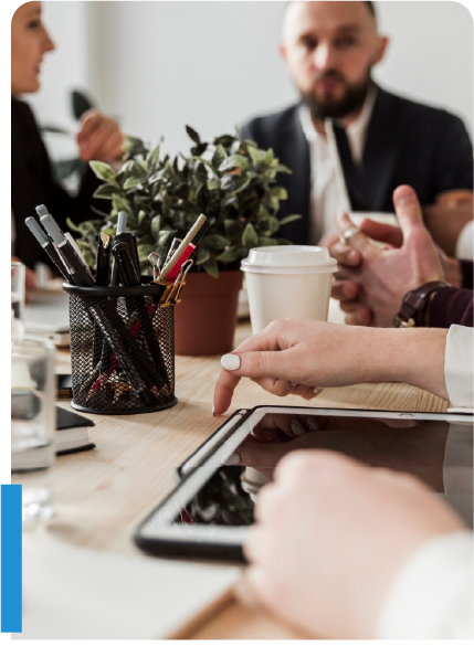 Group of professionals collaborating at a table with digital tablet and documents, planning an insurance agency sale.